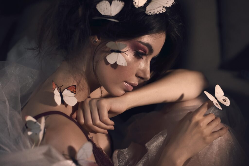 Artistic portrait of a woman with closed eyes and butterflies, showcasing elegance in a studio setting.