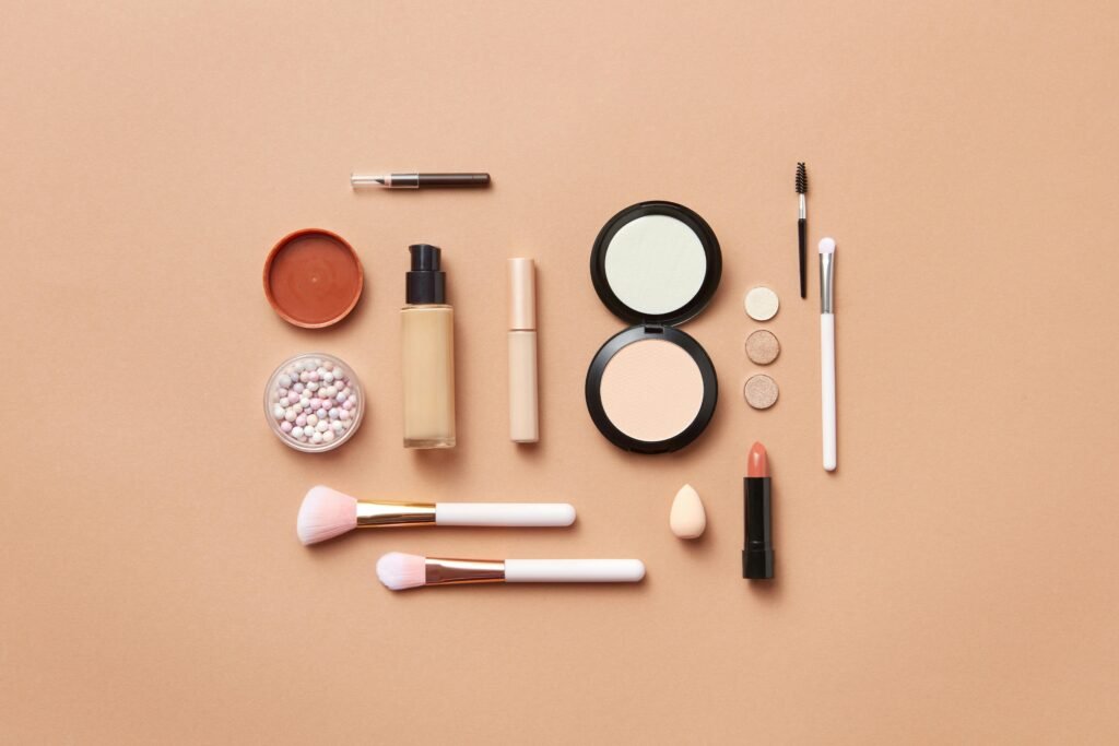 Stylish flatlay of various makeup products on a soft peach background.