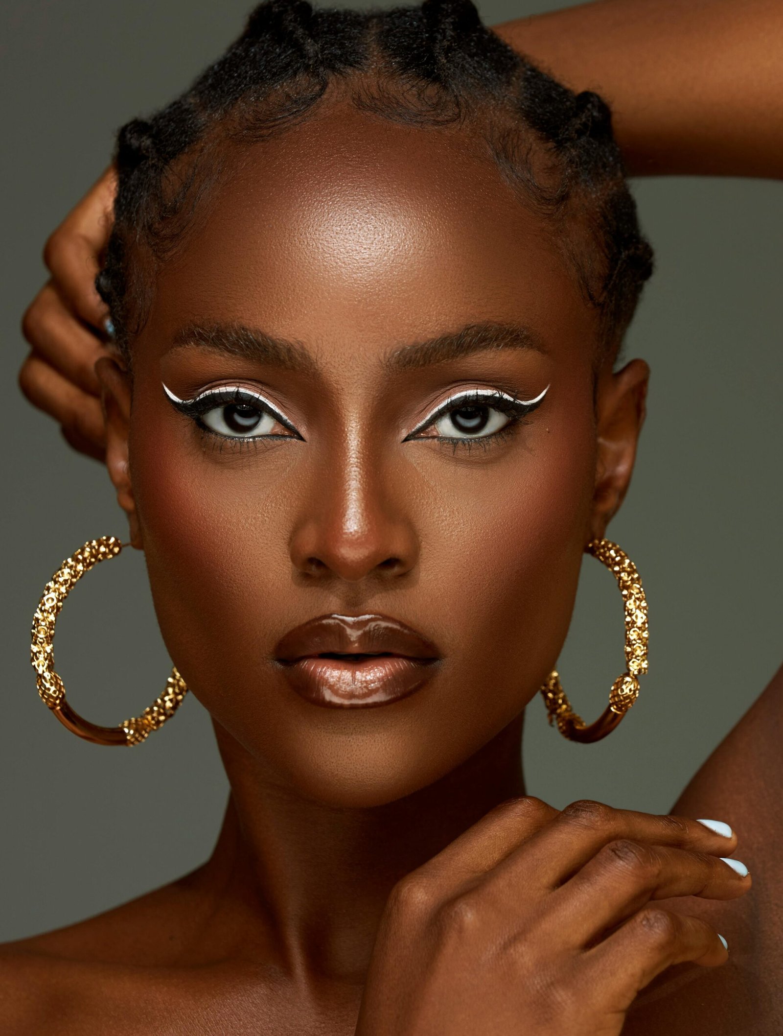 Stunning studio portrait of a woman with striking makeup and gold earrings, capturing elegance and fashion.