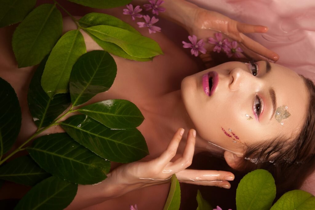 A serene portrait of a woman surrounded by green leaves and pink flowers in a bath.
