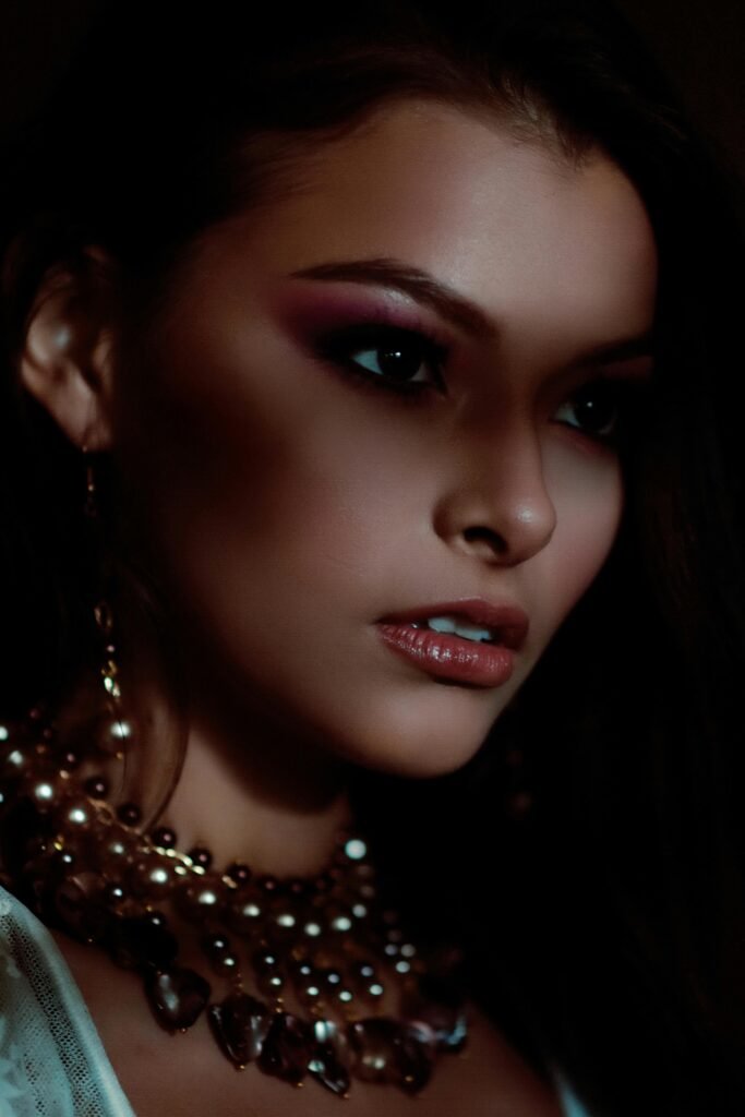 A striking portrait of a woman wearing vibrant makeup and a beaded necklace, emphasizing elegance.