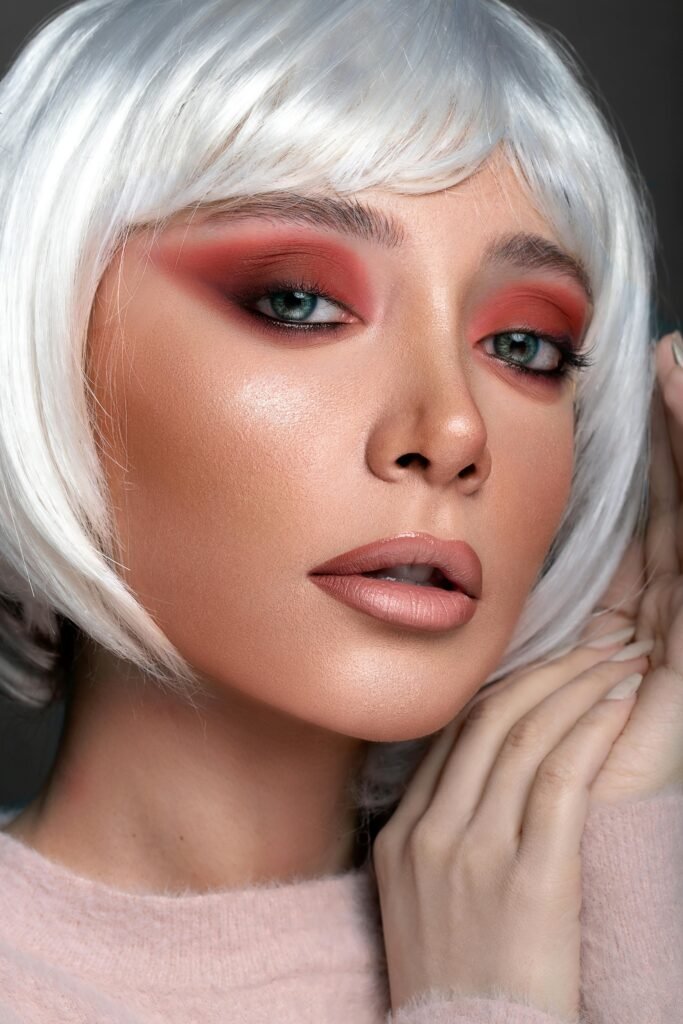 Close-up portrait of glamorous woman with red eye makeup and white wig.