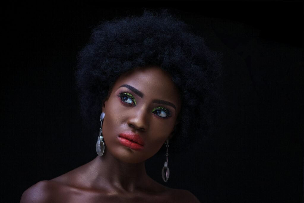 Close-up portrait of a beautiful black woman with striking makeup and elegant jewelry.