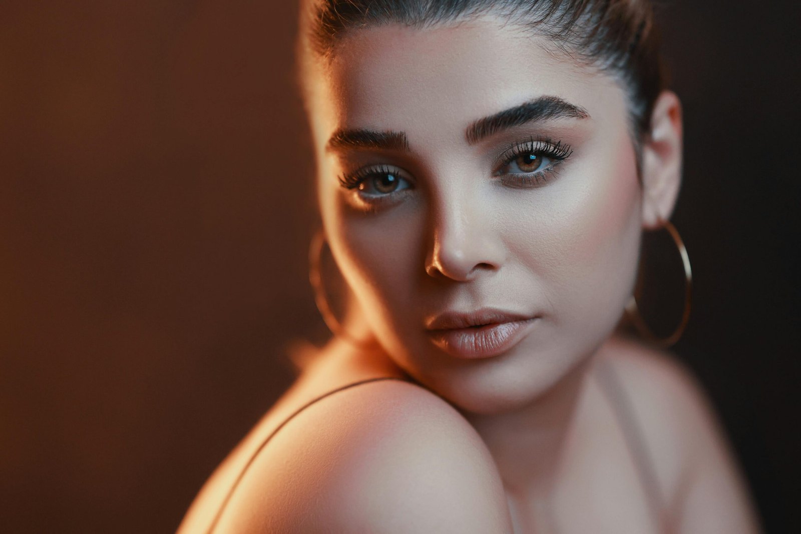 Contact Stunning close-up portrait of a woman with elegant makeup and soft lighting.