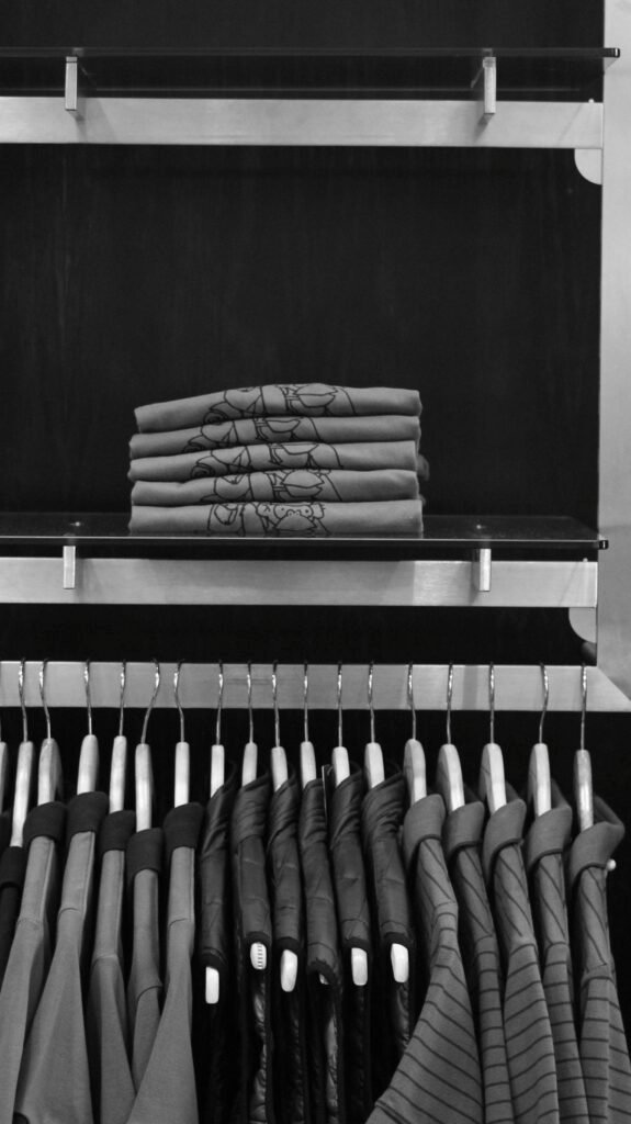 Elegant black and white display of folded shirts and hanging jackets in a store.